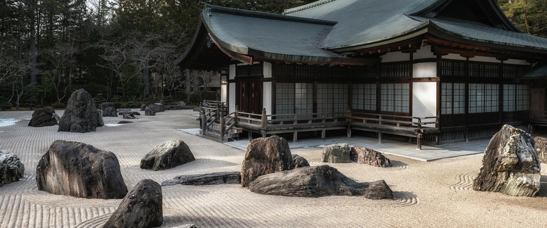 Raked zen rock garden in front of a temple hall