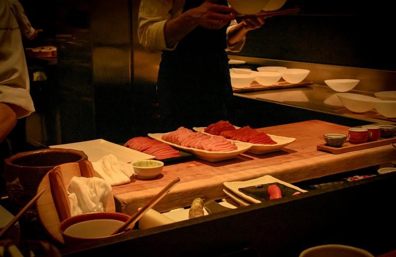 Chef preparing cuts of tuna at a sushi counter